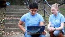 Two Pomeroy Scholars sitting on stairsteps looking at laptop